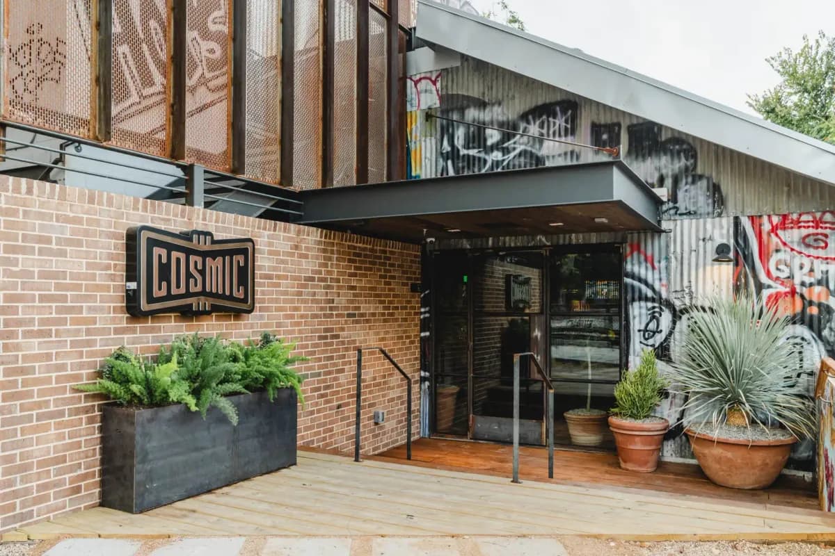 Cosmic Saltillo brick and corrugated metal storefront with graffiti mural, planters and entry steps
