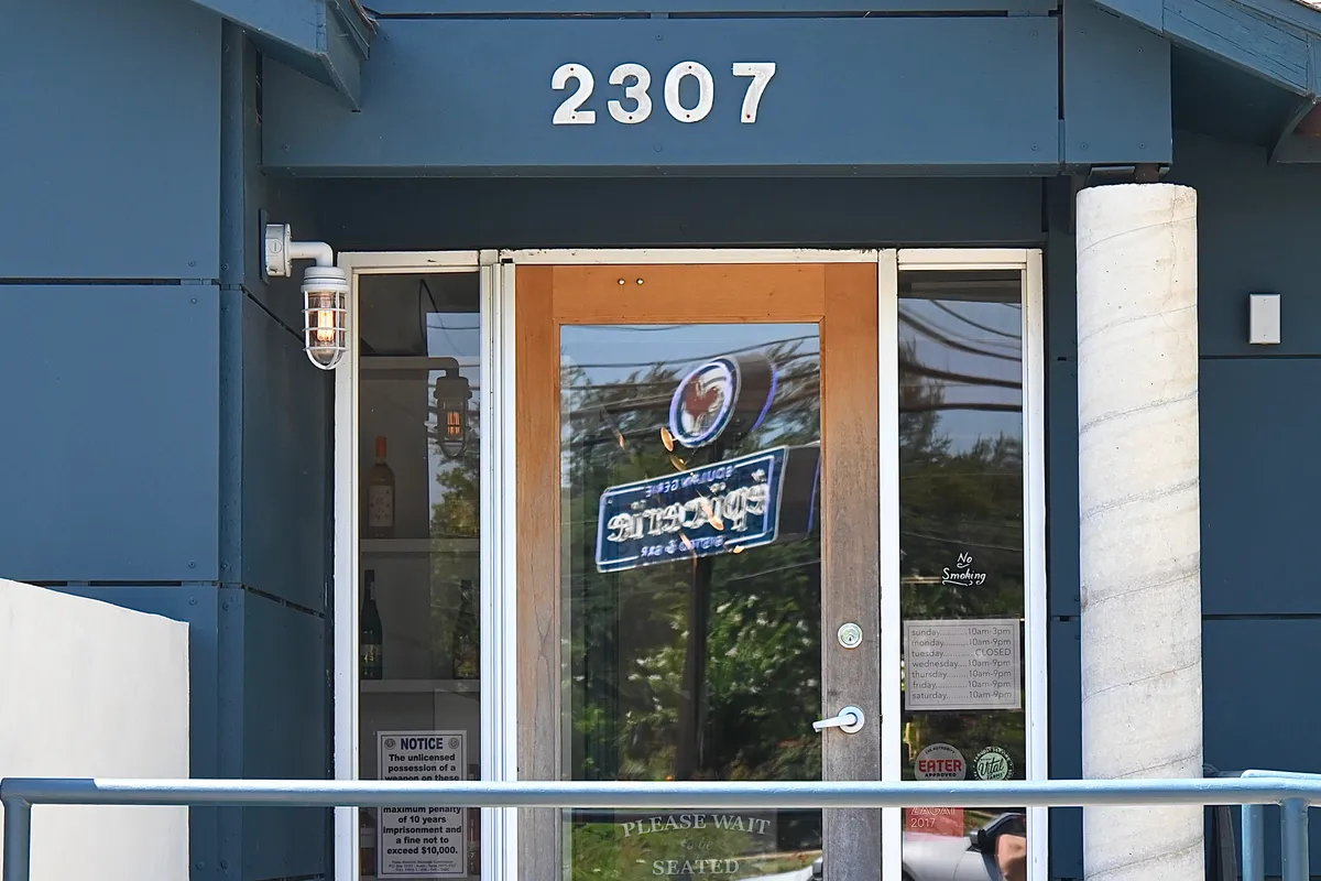 Navy blue entrance with number 2307 over glass door and trees alongside