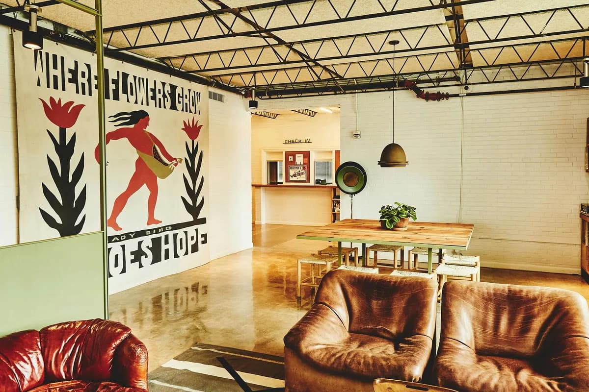 Carpenter Hotel lobby in the 1948 union hall building, with leather armchairs, a community table, record shelves and a mural
