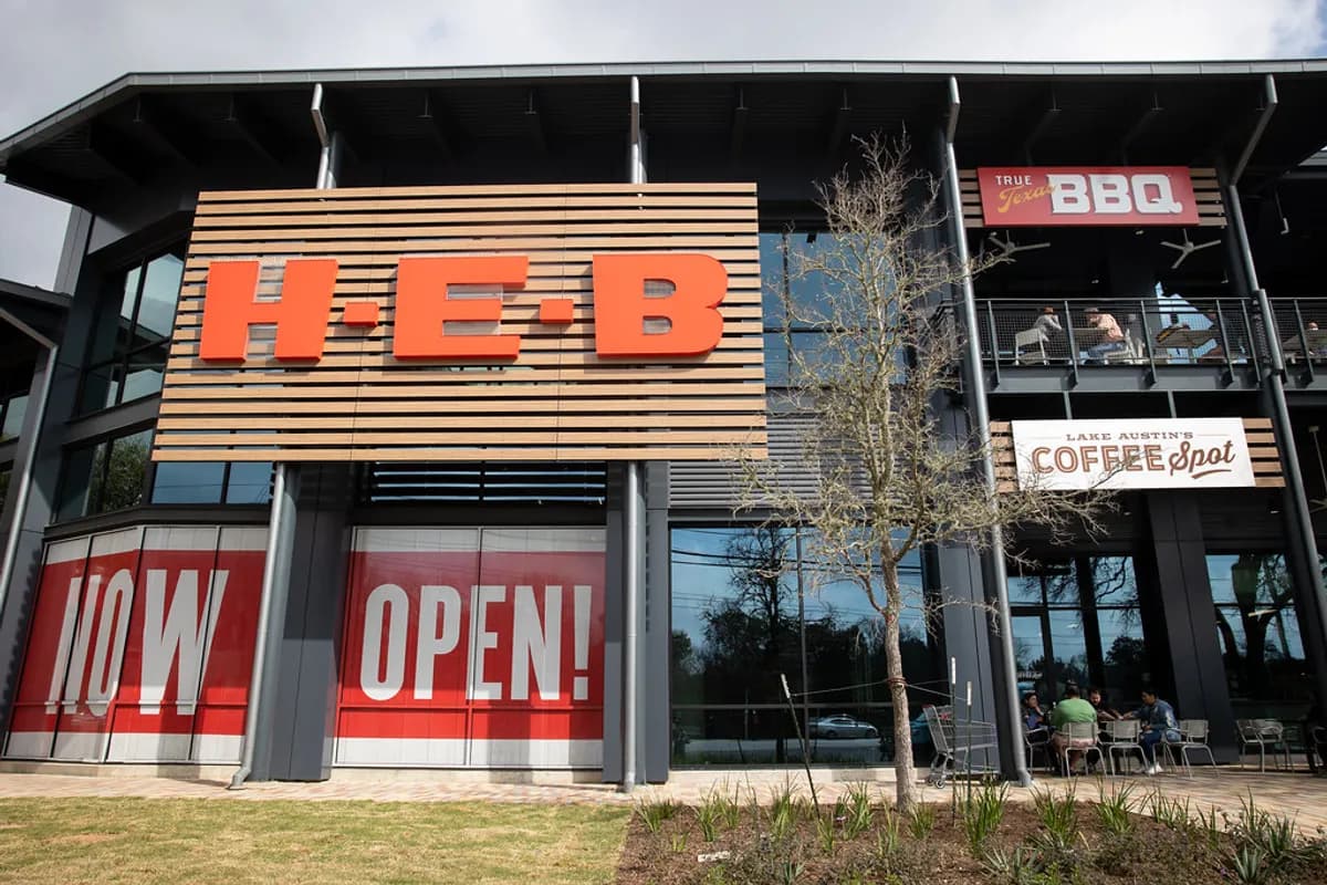 Lake Austin H-E-B storefront with the Lake Austin's Coffee Spot sign and customers seated at outdoor tables beneath it