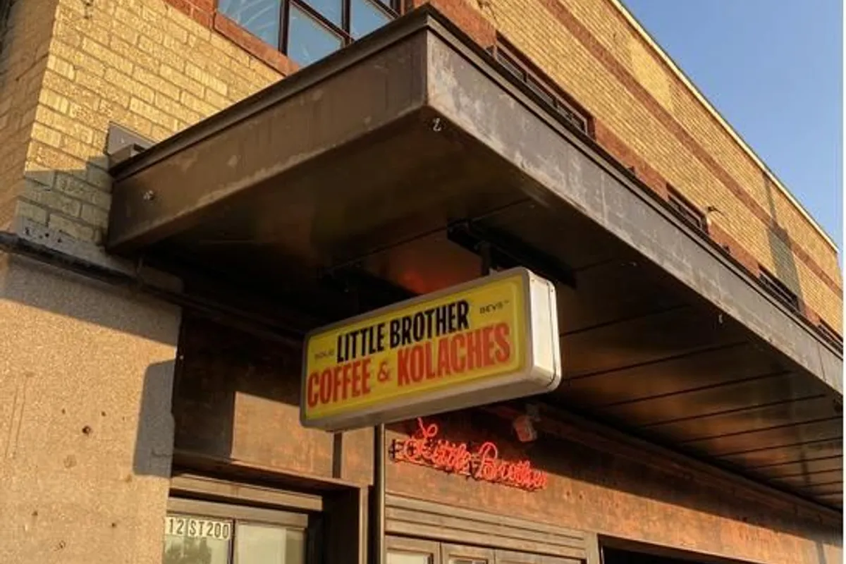 Little Brother Coffee & Kolaches storefront with yellow sign and red neon script under a brick awning