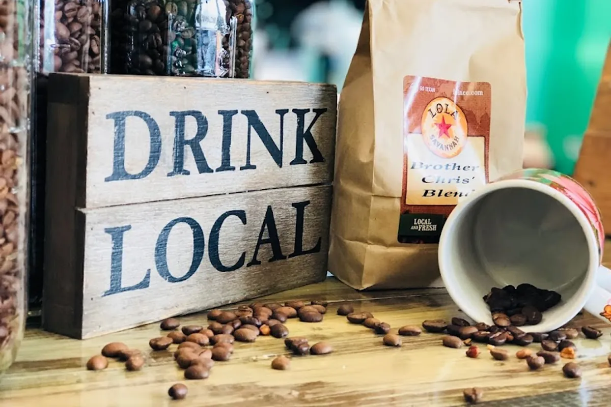 Lola Savannah Brother Chris' Blend bag beside a Drink Local sign, jars of beans and a mug