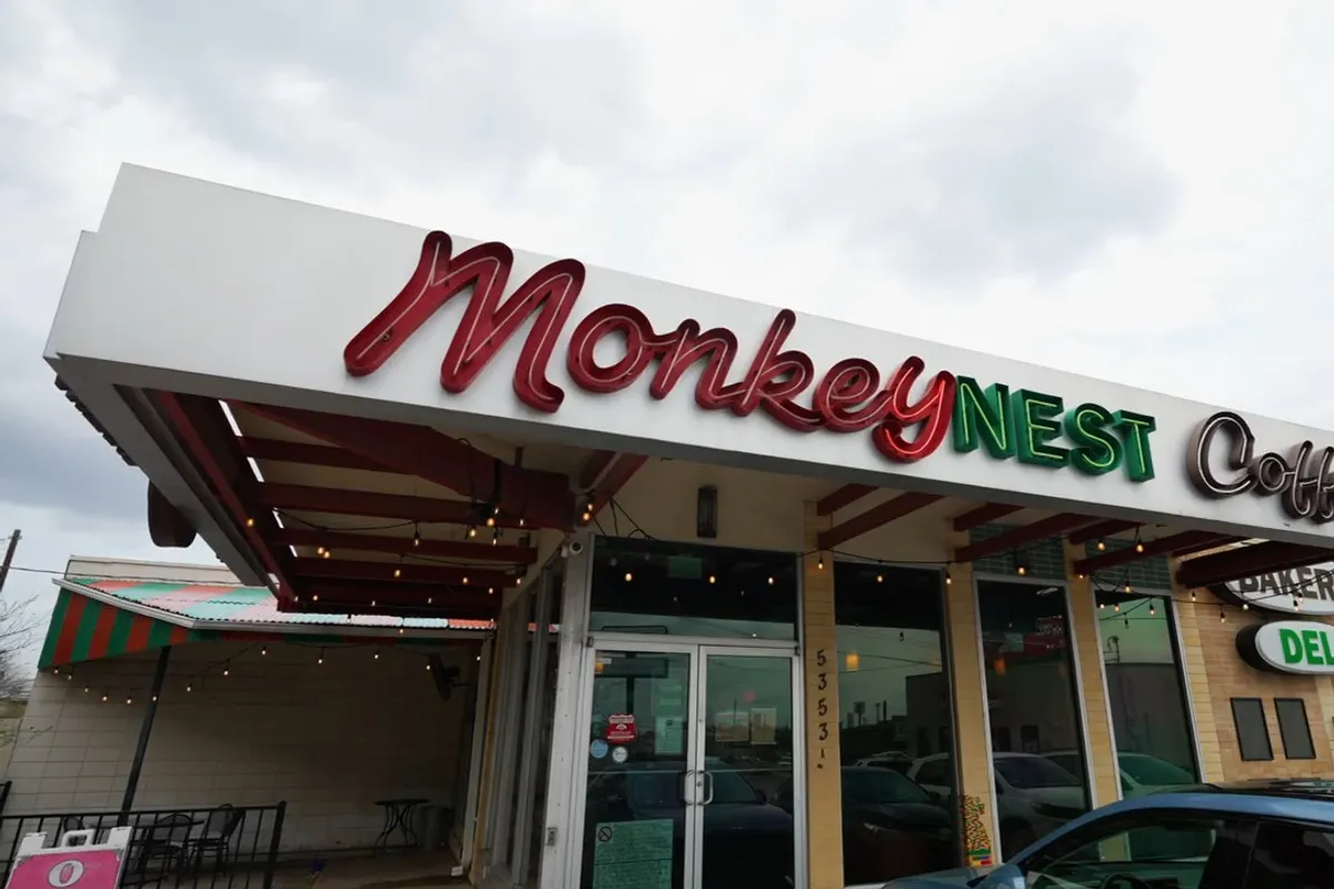 Monkey Nest Coffee storefront on Burnet Road with neon script sign, string lights and covered patio