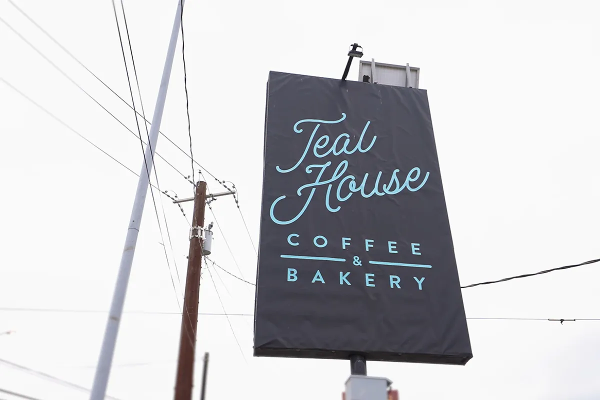 Teal House Coffee and Bakery street sign against sky with power lines