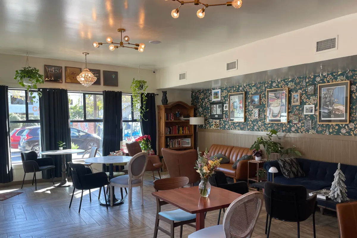 Bright cafe lounge with chandeliers, floral wallpaper, tables and sofas